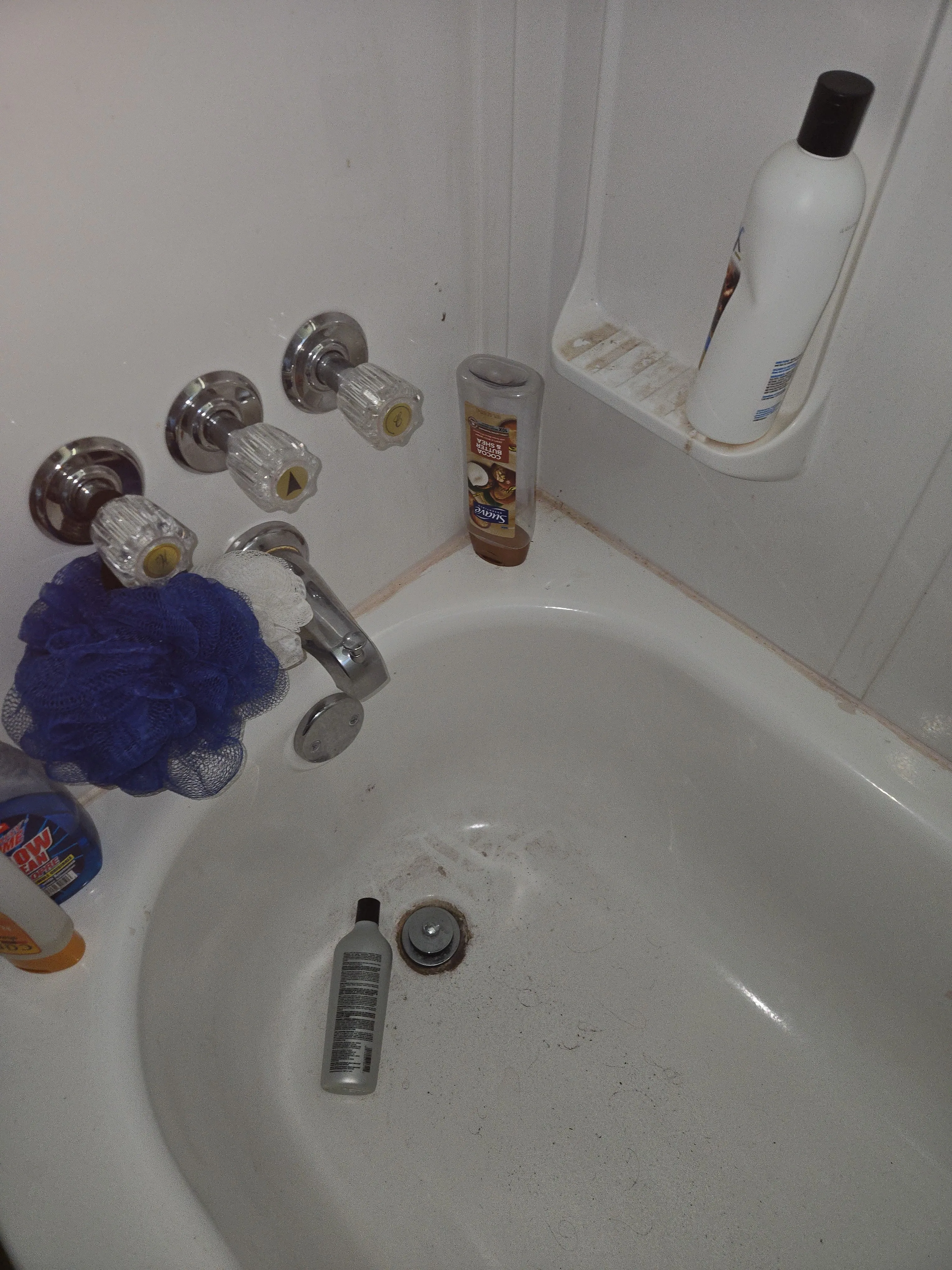 Bathtub before cleaning with visible residue around the basin and shower shelves