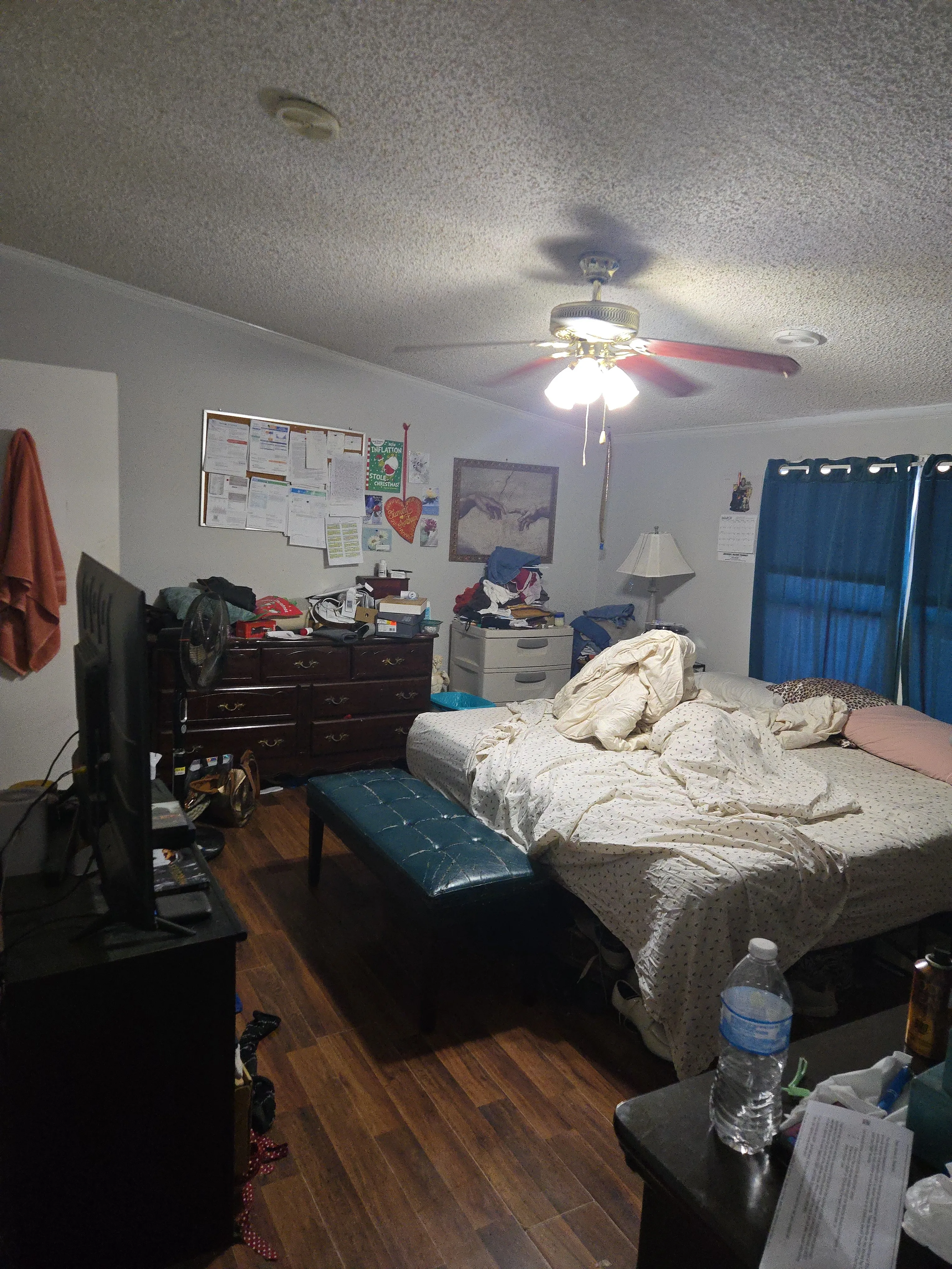 Bedroom before cleaning with items on the floor and an unmade bed