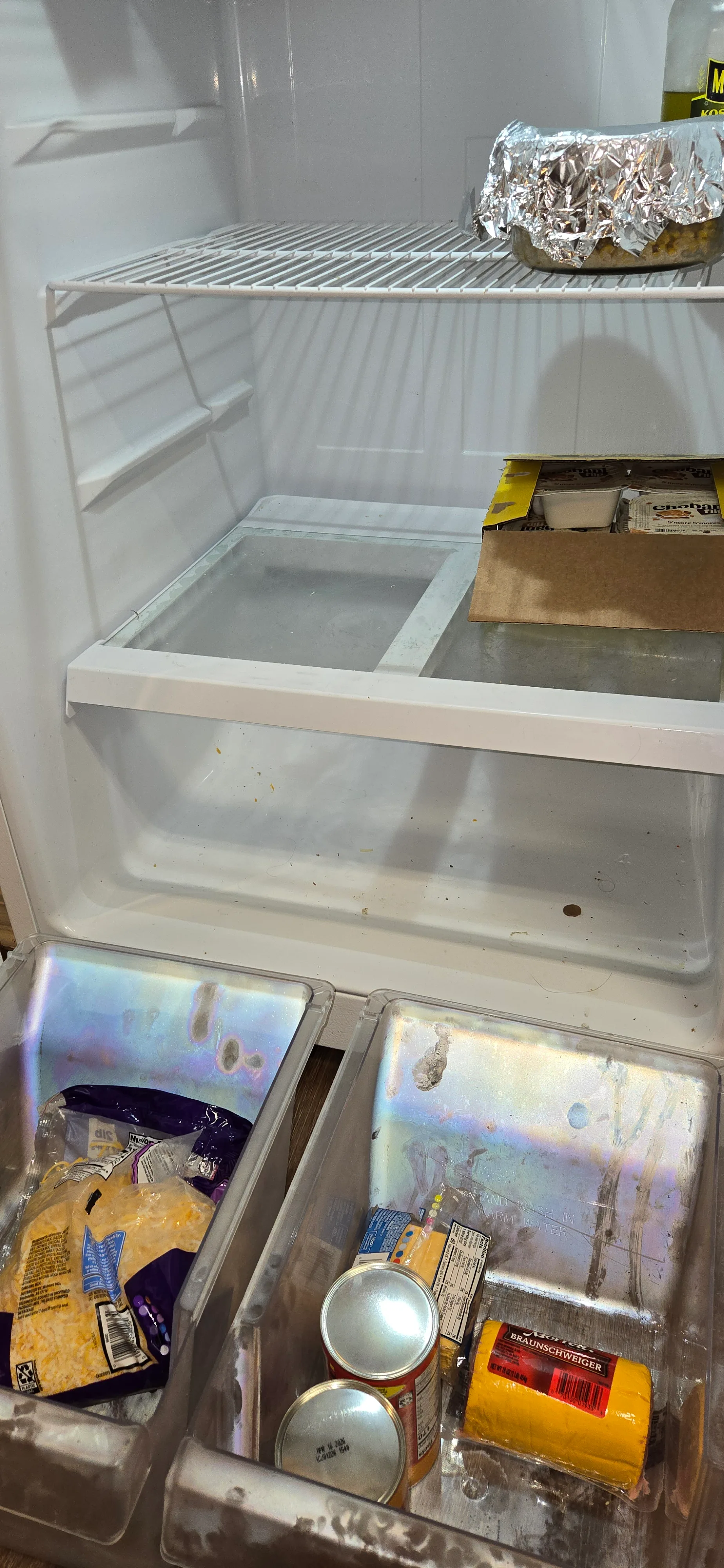 Refrigerator interior before cleaning with dirty drawers, residue, and food still inside
