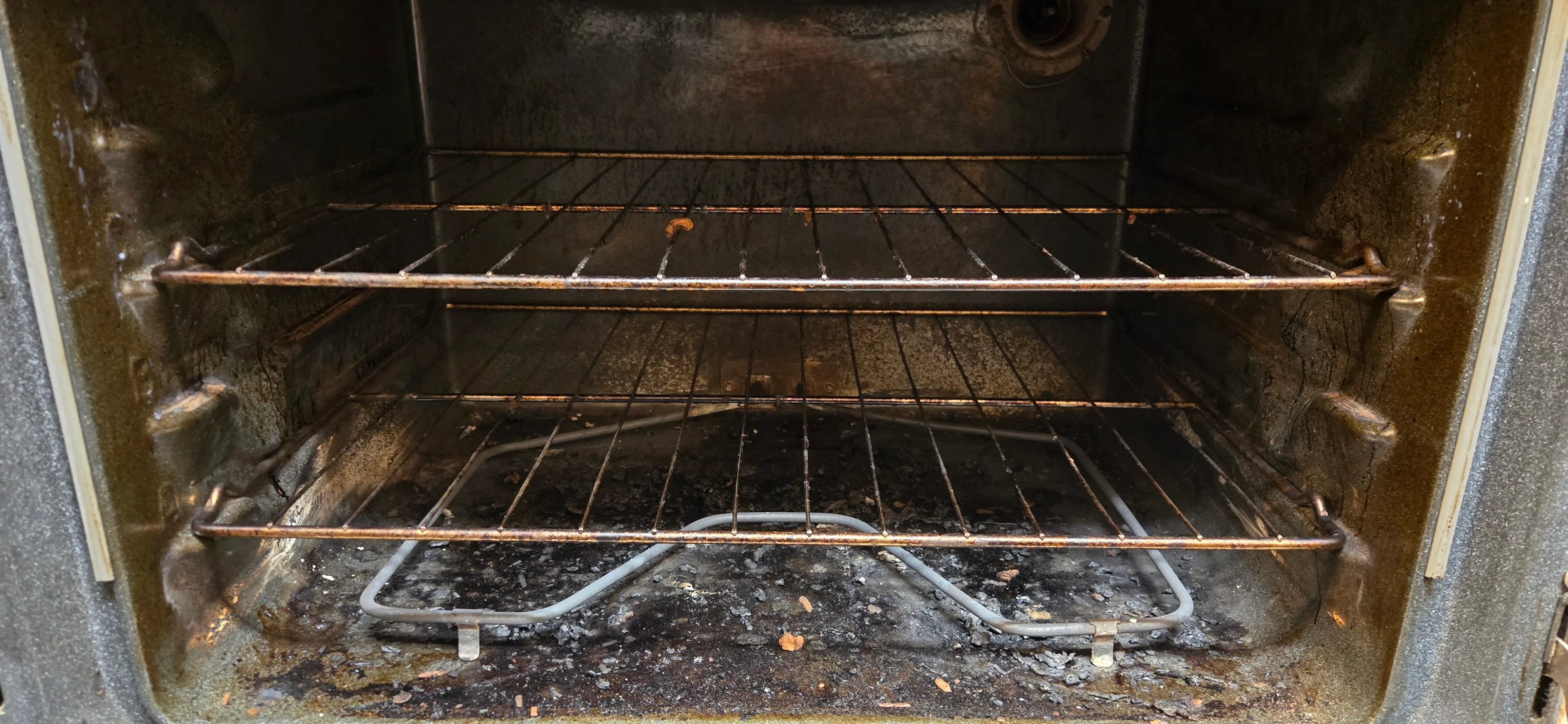 Oven interior before cleaning with heavy burnt buildup and grease